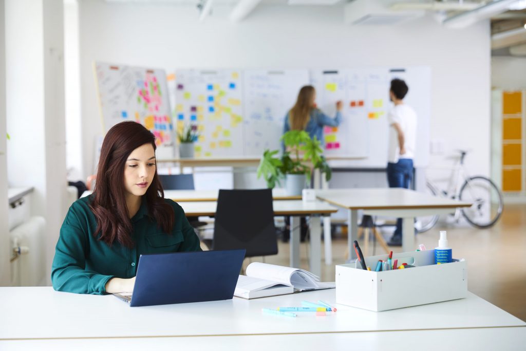 Entrepreneurs working in Openlab's bright co-working space equipped with portable whiteboards for collaborative projects and hight-adjustable desks.