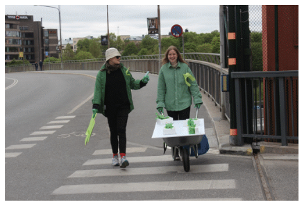 Participants in Openlab's master's course, dressed in green, with a cardboard prototype of the idea Green Backyard Network.